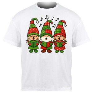 May include: White t-shirt featuring a cartoon illustration of three singing gnomes wearing Christmas hats. The gnomes are dressed in green and red outfits and are holding green books. Musical notes are above the gnomes.