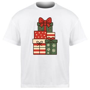 Può includere: T-shirt bianco con una pila di scatole regalo illustrate. Le scatole sono in vari colori, tra cui rosso, verde e crema, e sono decorate con pois, strisce e fiocchi di neve. Un grande fiocco rosso è in cima alla scatola superiore.