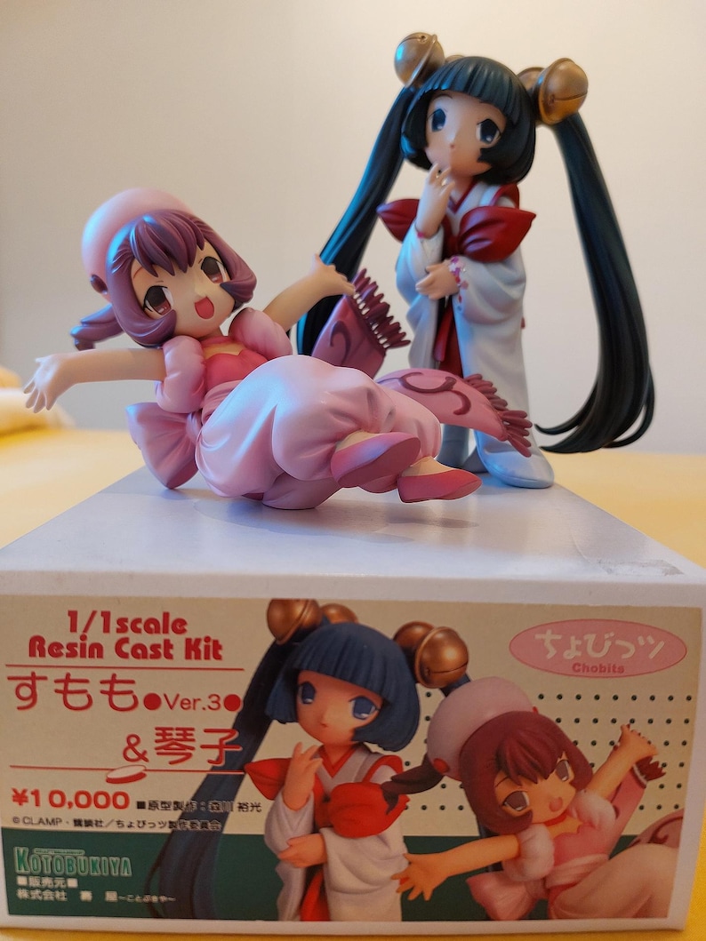 May include: A 1/1 scale resin cast kit of two anime characters, one in a pink kimono and the other in a white kimono. The box is labeled "Chobits" and features the text "1/1 scale Resin Cast Kit, Sumomo Ver. 3 & Kotoko, &yen;10,000, &copy;CLAMP・Kodansha/Chobits, Kotobukiya."