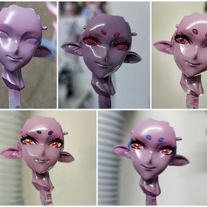 May include: Four stages of painting a pink resin figurine of a humanoid head with large eyes and pointed ears. The figurine is on a stick and the stages show the progression of painting the eyes and face.