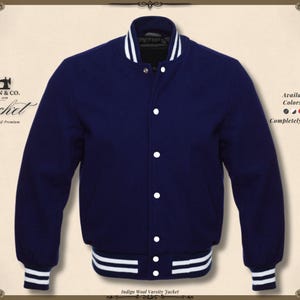 May include: Indigo wool varsity jacket with white accents on the collar, cuffs, and hem. The jacket has a button-up front and features the text "KHAN & CO. Jacket Handmade & Premium". Available in all colors and sizes, completely customizable.