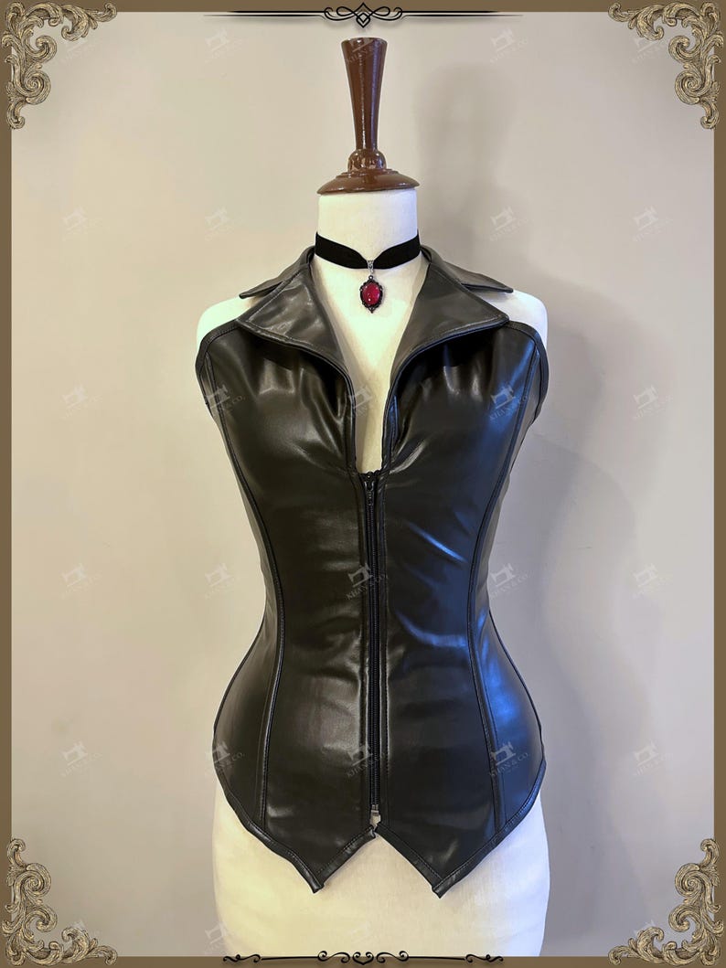 May include: A black faux leather corset with a zipper closure and a collared neckline. A black choker necklace with a red pendant is worn around the neck. The corset is displayed on a mannequin.