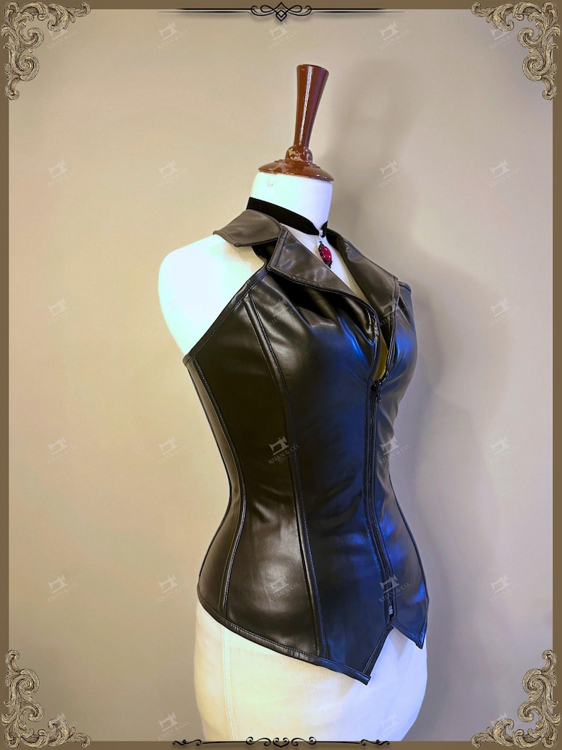 May include: A black faux leather corset with a halter neckline and a front zipper. The corset is displayed on a mannequin with a black choker and a red pendant. The garment has a tailored fit and a structured design.