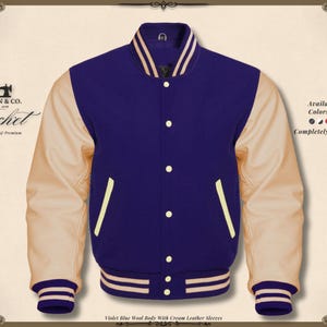 May include: A varsity jacket with a violet blue wool body and cream leather sleeves. The jacket has a button-up front, cream-colored accents, and striped cuffs and hem. The text "KHAN & CO." and "Jacket" are visible.