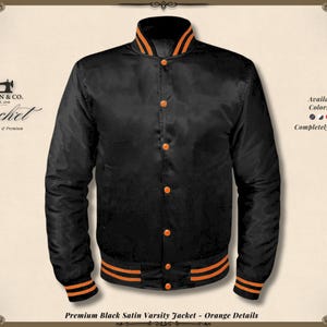 May include: Black satin varsity jacket with orange detailing. It has a button-up front, ribbed cuffs, collar, and hem with orange stripes. The jacket features the text "KHAN & CO." and "Jacket" on the left. The text "Available in All Colors & Sizes" is on the right.