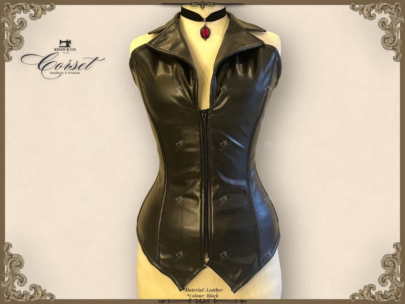 May include: Black leather corset with a collared neckline and a front zipper closure. The corset has a fitted silhouette and is displayed on a mannequin. A black choker with a red pendant is worn around the mannequin's neck. The corset is handmade.
