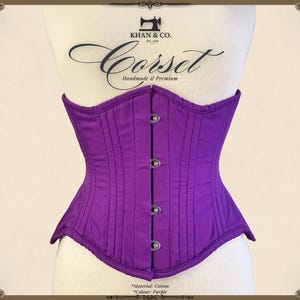 Op de afbeelding: Paarse katoenen corset met een busk sluiting en stalen baleinen. Het corset is handgemaakt en heeft een label met de tekst "Khan & Co. Corset Handgemaakt & Premium".
