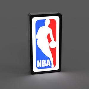 以下が含まれることがあります： NBAのロゴが入った長方形の看板。ロゴは、青と赤の背景に、ボールをドリブルするバスケットボール選手の白いシルエットが描かれています。「NBA」の文字は白です。