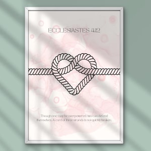 May include: Framed art print featuring a black rope heart design on a pink and white watercolor background. The text "ECCLESIASTES 4:12" is at the top, with a quote below about strength in unity. A decorative piece for home decor.