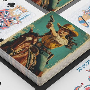 May include: A deck of playing cards with a vintage Western theme. The card backs and the face cards feature illustrations of a cowgirl on a horse, holding a gun. Other cards show traditional suits and a joker card.