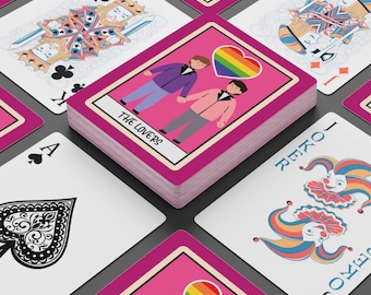 May include: A deck of playing cards with a pink border. The deck features a card with two figures holding hands and a rainbow heart. Other cards include a King of Clubs, an Ace of Spades, and a Joker card.