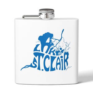 May include: A white stainless steel hip flask with a silver cap and hinge. The flask has a blue graphic of a map with the words "Lake St. Clair" in a stylized font. The flask is rectangular.