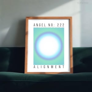 May include: A framed print with the text "ANGEL NO: 222" and "ALIGNMENT". The artwork features a central white circle with a blue and green gradient background. The frame is made of wood and is displayed on a dark green couch.