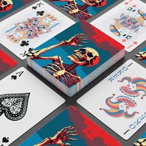 May include: A deck of playing cards with a skeleton design. The cards feature a blue, red, and cream color scheme. The deck is surrounded by other cards, including a Joker card and a King of Clubs.