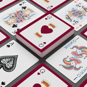 May include: A deck of playing cards with a red border, featuring various card suits and face cards. The Queen of Hearts is prominently displayed, with a red heart and crown. Other cards include the King of Clubs, Ace of Spades, and a Joker card.