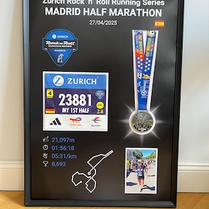 May include: Framed black display featuring a Madrid Half Marathon medal, race bib, and event details. The text "Zurich Rock 'n' Roll Running Series MADRID HALF MARATHON" is displayed at the top, with the date 04/27/2025.