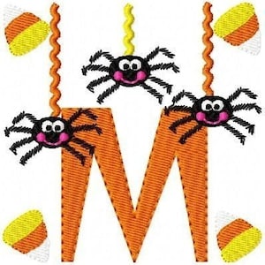 May include: Orange letter M with three black spiders hanging from it with yellow and white candy corn on either side of the letter.