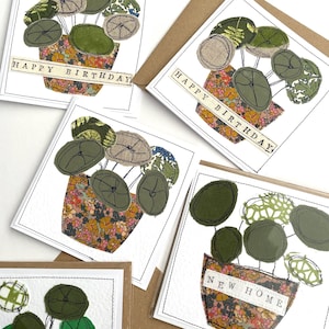 May include: A collection of square greeting cards featuring fabric collage artwork of potted plants. Each card displays a plant with round green leaves in a floral patterned pot. Some cards feature the text HAPPY BIRTHDAY or NEW HOME on a strip.