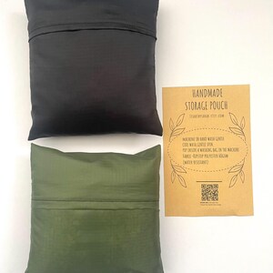 May include: Two handmade storage pouches, one black and one olive green, are shown on a white surface. A brown card with product care and material details is placed beside the pouches.