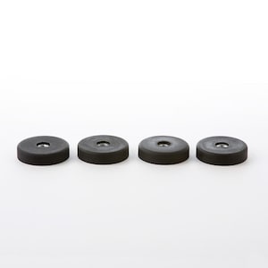 Könnte beinhalten: Vier runde schwarze Möbelgleiter mit einem kleinen Loch in der Mitte.