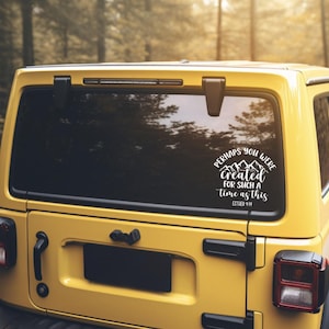 Könnte beinhalten: Ein gelber SUV mit einem weißen Aufkleber auf der Heckscheibe. Der Aufkleber zeigt den Text "Perhaps you were created for such a time as this" mit einer Berg-Grafik. Das Fahrzeug steht in einem Waldgebiet.