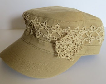 May include: A khaki colored baseball cap with a white crocheted trim and a large white crocheted flower accent.