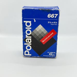 Könnte beinhalten: Blaue Polaroid 667 Packfilm-Box. Die Box zeigt das weiße Polaroid-Logo, den Filmtyp und eine Graustufen-Grafik. Die Box misst 8,26 x 10,80 cm.