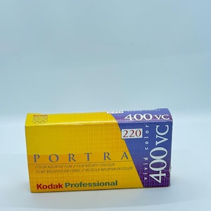 May include: A yellow and purple Kodak Portra 400 VC 220 film box. The box features the Kodak logo, the text "PORTRA", and the words "COLOR NEGATIVE FILM" in multiple languages. The box is designed for professional use.