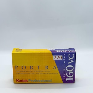 May include: A yellow and purple Kodak Portra 160 VC 220 color negative film box. The box has the text "PORTRA" and "COLOR NEGATIVE FILM" printed on it. The box is rectangular and has a white background.
