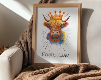 May include: A framed watercolor print featuring a Highland cow wearing a gold crown. The cow has orange, yellow, and blue fur, with the text "Posh Cow" below. The artwork is displayed on a beige couch with a brown blanket.
