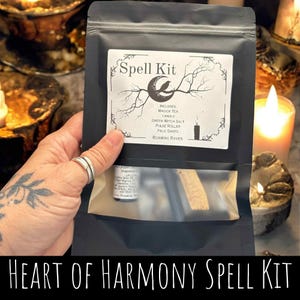 Könnte beinhalten: Ein schwarzer Beutel mit der Aufschrift "Spell Kit" und einem Mond- und Raben-Design. Das Set enthält Magie-Tee, eine Kerze, grünes Hexensalz, eine Pulswalze, Palo Santo und "Roaming Raven"-Produkte. Der Text "Heart of Harmony Spell Kit" befindet sich unten.