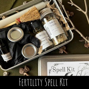 May include: A fertility spell kit in a metal tin, containing a white candle, a small broom, glass jars with herbs, and bottles of oil. The kit includes the text "Fertility Spell Kit" and "Herbs of Creation".