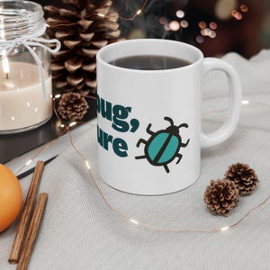 May include: White ceramic mug with the words "Bug, Sure" in teal and a teal and black beetle graphic. The mug is filled with a dark liquid and has a curved handle. The mug is on a light grey surface.