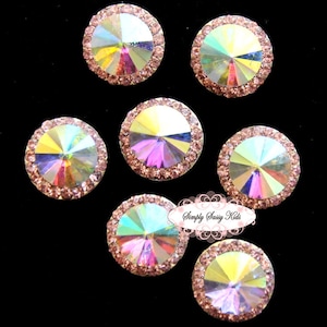 May include: Seven iridescent pink and clear rhinestones with a silver backing. Each rhinestone has a smaller circle of pink rhinestones surrounding the centre.