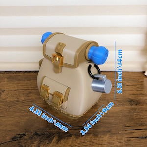 May include: A tan and brown backpack-style container with gold-colored clasps and a blue cylindrical top. The container is 4.33 inches (11cm) wide, 3.54 inches (9cm) deep, and 5.51 inches (14cm) tall. A silver-colored lock hangs from a black loop.