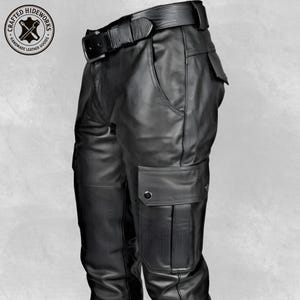 Könnte beinhalten: Schwarze Leder-Cargohose mit passendem Gürtel. Die Hose hat mehrere Taschen, darunter zwei Cargotaschen an den Beinen. Der Gürtel hat eine silberne Schnalle. Handgefertigte Lederwaren.