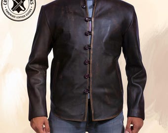 May include: A brown leather jacket with a high collar and button closures. The jacket has a distressed finish and long sleeves. The image includes a circular logo with the text "Crafted Hideworks Handmade Leather Goods."