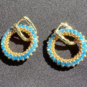 Pendientes transformables Congo con anillas extraíbles de cuentas doradas, azules y blancas.