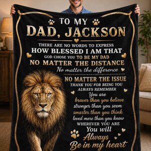 Op de afbeelding: Zwarte fleece deken met een gouden leeuwenafbeelding en de tekst "TO MY DAD, JACKSON" en een liefdevolle boodschap. Een gepersonaliseerd cadeau, ideaal voor een vader.