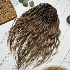 Puede incluir: Un conjunto de extensiones de cabello que presenta una combinación de mechones trenzados de color marrón oscuro y piezas de cabello largo y ondulado de color marrón claro. El cabello está dispuesto en cascada con trenzas y ondas sueltas.