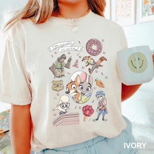 A person wearing a white t-shirt with a cartoon-style illustration of various cartoon characters, including a dog, a rabbit, and other animals, along with a smiley face.