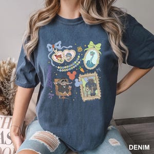 A woman wearing a blue t-shirt with various cartoon-style illustrations and text.