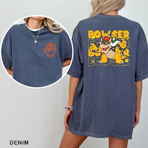 A denim t-shirt with a graphic of a character from the Mario video game franchise, specifically Bowser, printed on the back.