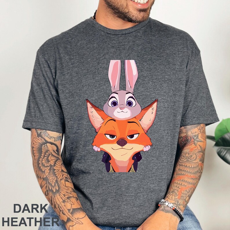 A man wearing a gray t-shirt with a graphic of a fox and a rabbit peeking out from behind it.
