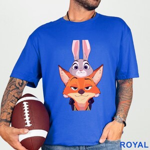 A man wearing a blue t-shirt with a cartoon image of a rabbit and a fox, holding a football.