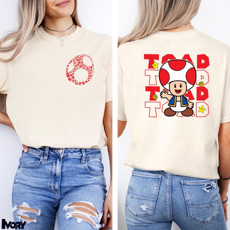 May include: An ivory t-shirt featuring a small red graphic on the front chest and a large graphic on the back. The back design displays the character Toad with the text TOAD repeated in red block letters, accompanied by yellow stars and gold coins.