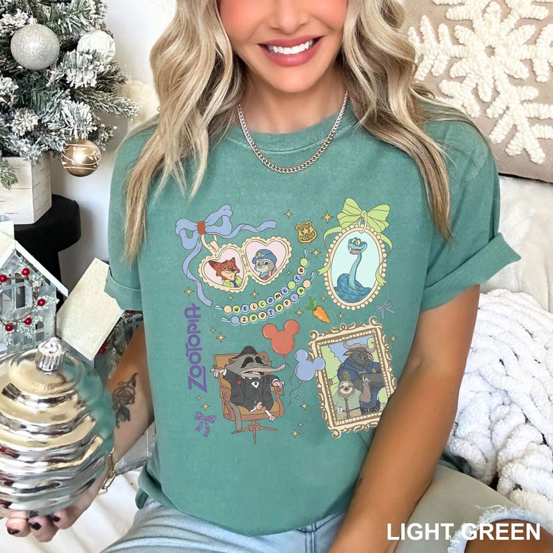 A smiling woman wearing a green t-shirt with various cartoon characters and designs printed on it.