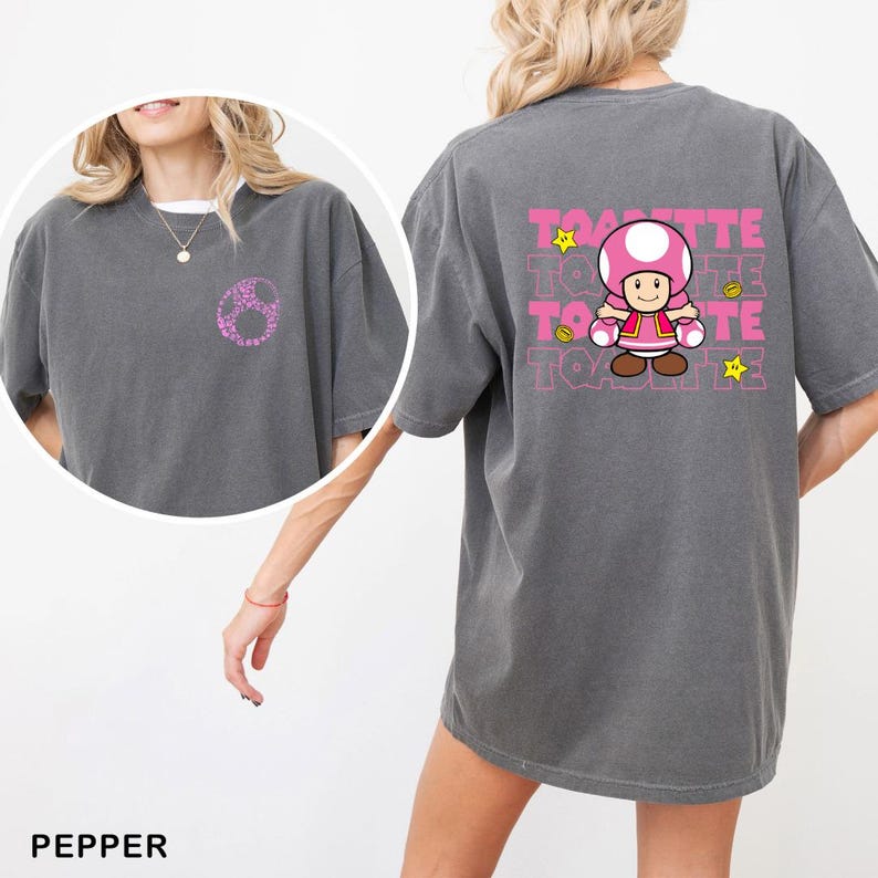 A woman wearing a gray t-shirt with a cartoon character and text printed on the back.