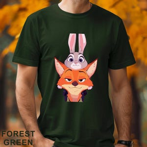 A green t-shirt with a graphic design featuring two cartoon animal characters, a fox and a rabbit, with the fox peeking out from behind the rabbit.