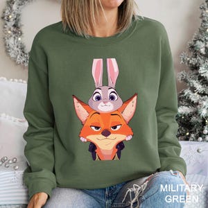 A woman wearing a green sweatshirt with a cartoon image of a fox and a rabbit on it.